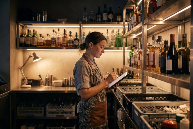 Barista controlla le scorte del bar con un tablet in un magazzino organizzato